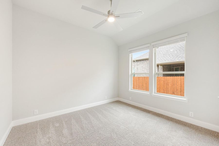 Empty bedroom with carpet flooring, ceiling fan, and double window with white trim