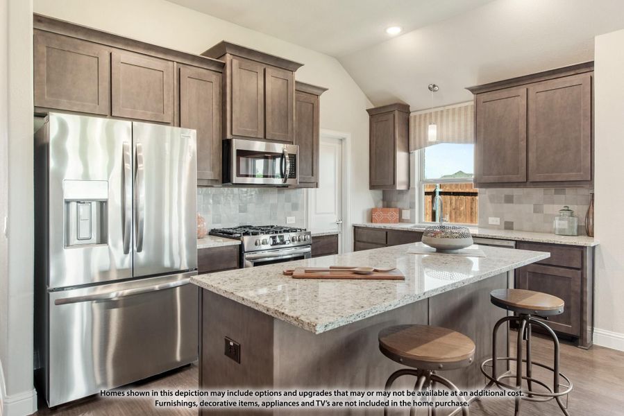 Kitchen with dark brown cabinets, granite island, stainless steel appliances, and two bar stools Kitchen with dark brown cabinets, granite island, stainless steel appliances, and two bar stools