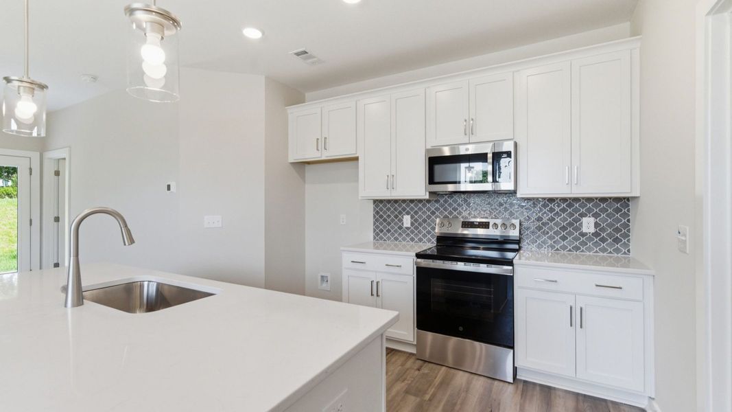 Kitchen with tile backsplash, pendant lighting, and quartz countertops Kitchen with tile backsplash, pendant lighting, and quartz countertops