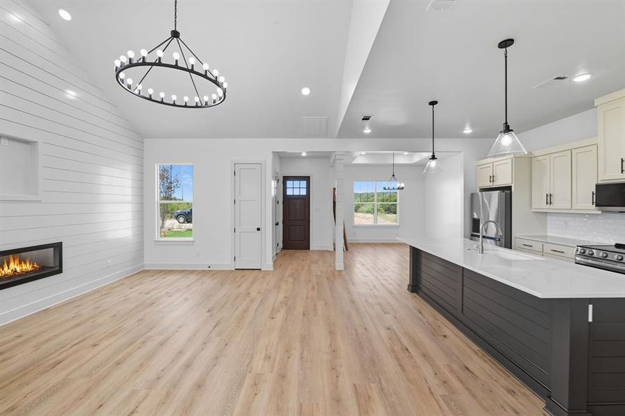 Kitchen featuring a chandelier, white cabinets, decorative light fixtures, light wood finished floors, and vaulted ceiling Kitchen featuring a chandelier, white cabinets, decorative light fixtures, light wood finished floors, and vaulted ceiling