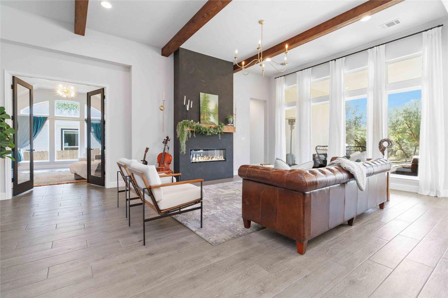 Living room with a chandelier, a fireplace, beamed ceiling, light wood-style flooring, and recessed lighting Living room with a chandelier, a fireplace, beamed ceiling, light wood-style flooring, and recessed lighting