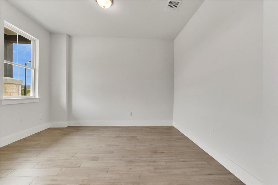 A spacious room offers ample natural light and durable, wood-look flooring.