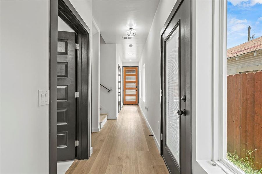 Hall with light wood-type flooring, stairs, and healthy amount of natural light Hall with light wood-type flooring, stairs, and healthy amount of natural light