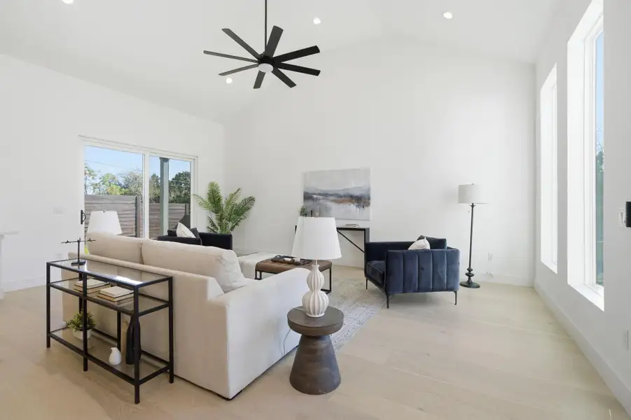 Living room featuring light wood-type flooring, a ceiling fan, recessed lighting, and vaulted ceiling