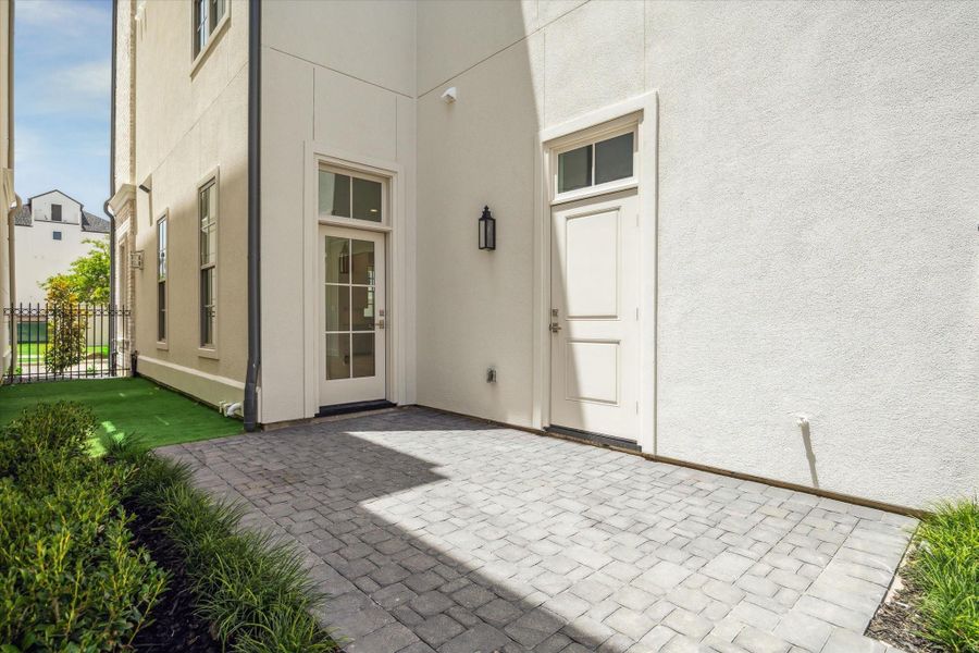 Private courtyard features patio and artificial turf, accessible from glass door in house, side door to garage and back gate from curb.