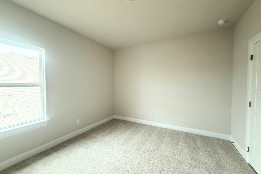 Bright room featuring neutral-toned carpeting and walls Bright room featuring neutral-toned carpeting and walls