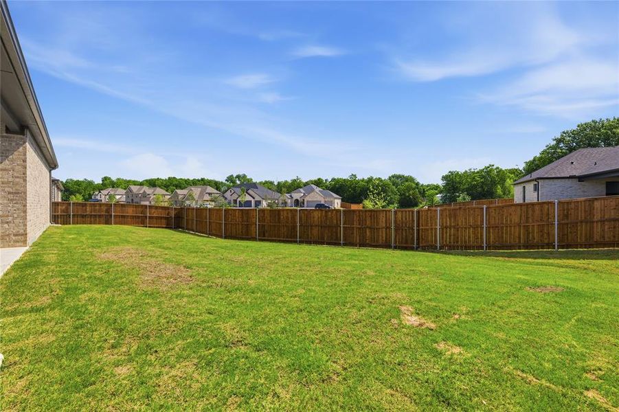 Expansive grassy yard area featuring a full privacy fence