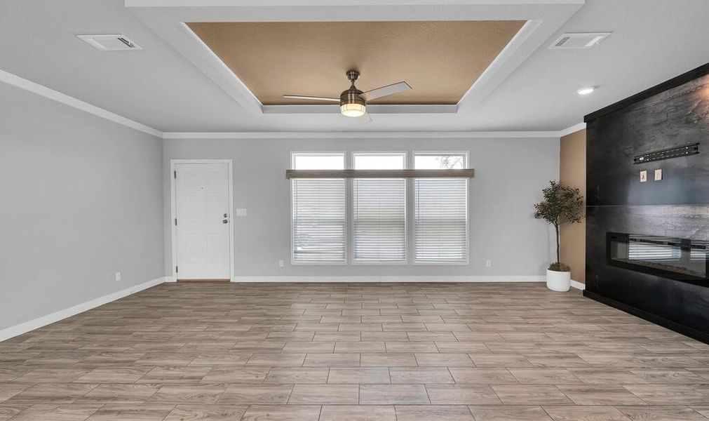 Foyer featuring ceiling fan, a raised ceiling, wood tiled floors, and crown molding Foyer featuring ceiling fan, a raised ceiling, wood tiled floors, and crown molding