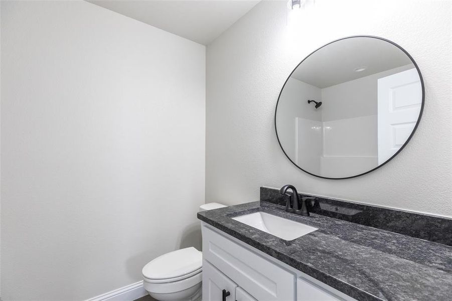 Bathroom vanity featuring a dark countertop, white undermount sink, and matte black faucet