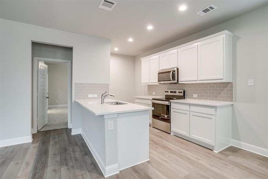 Kitchen with stainless steel appliances, light wood finished floors, light countertops, and visible vents