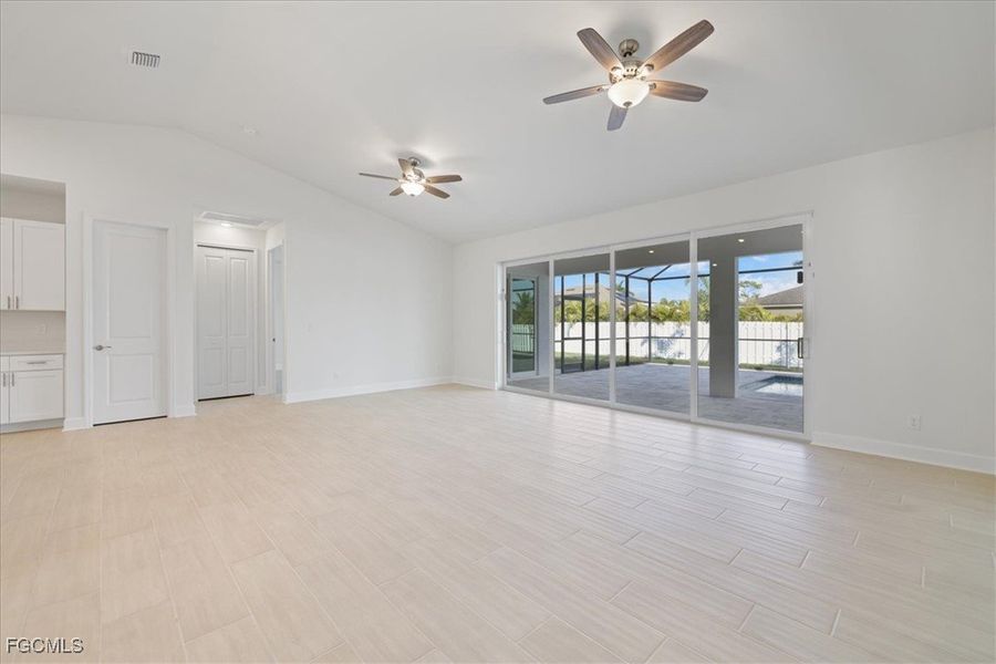 Empty room featuring vaulted ceiling, wood tiled floors, and a ceiling fan Empty room featuring vaulted ceiling, wood tiled floors, and a ceiling fan