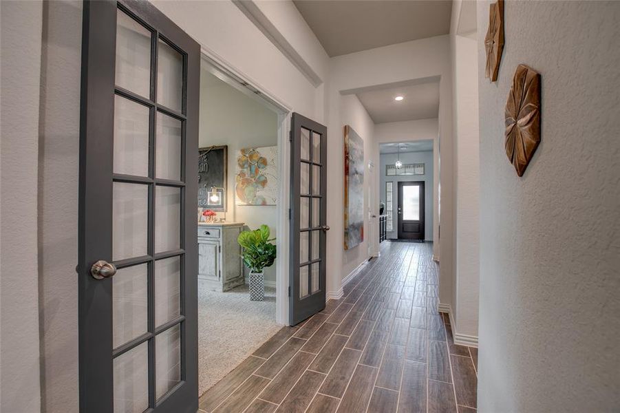 Hallway with wood tiled floors, french doors, recessed lighting, and a textured wall Hallway with wood tiled floors, french doors, recessed lighting, and a textured wall