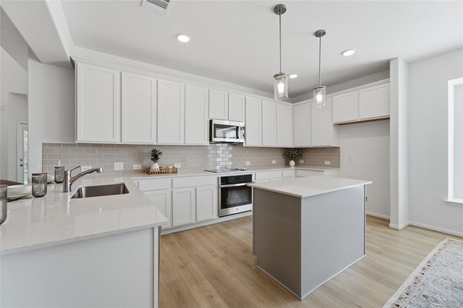 A contemporary kitchen features bright white cabinetry and gleaming countertops. A contemporary kitchen features bright white cabinetry and gleaming countertops.