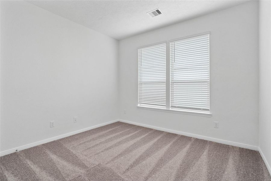 This secondary bedroom with the large windows offers plenty of natural lighting! It also features plush carpeting, neutral paint tones, recessed lighting, and a walk-in closet.