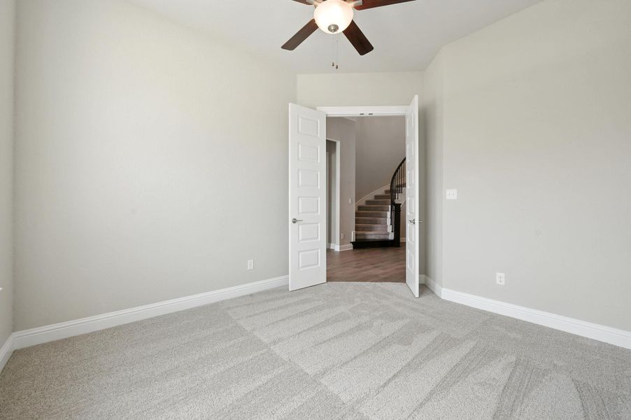 Unfurnished bedroom with light carpet and a ceiling fan
