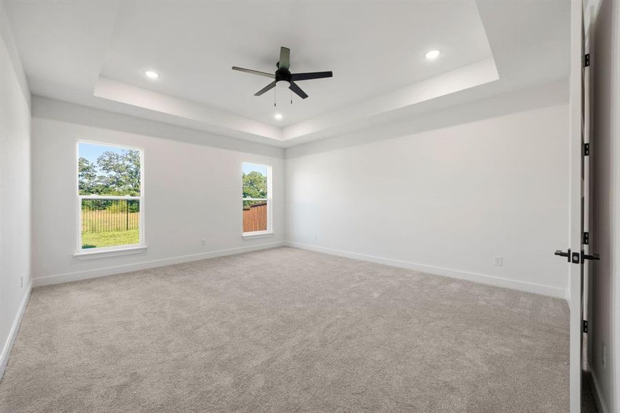 Spacious room featuring a tray ceiling, recessed lighting, and a ceiling fan Spacious room featuring a tray ceiling, recessed lighting, and a ceiling fan