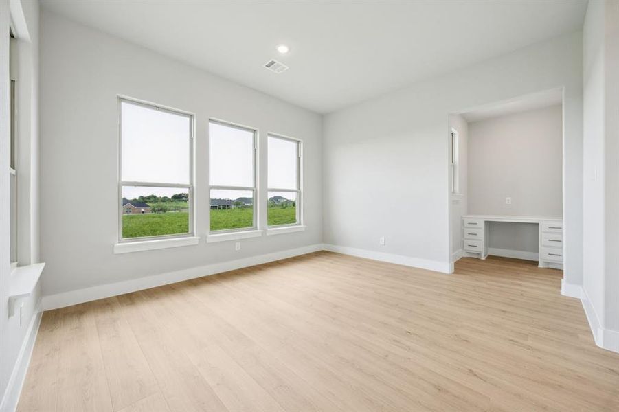 Unfurnished bedroom featuring built in study area, light wood finished floors, and recessed lighting