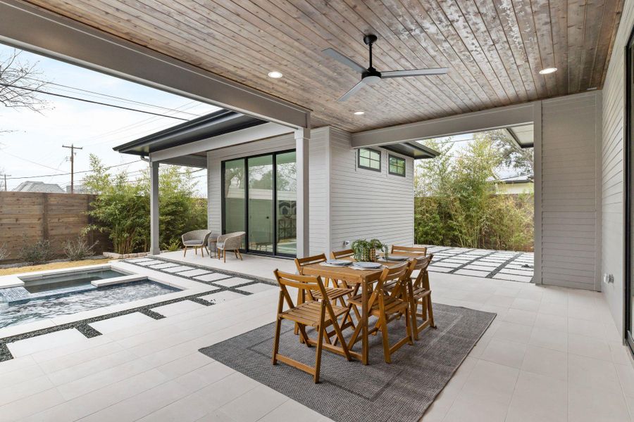 View of patio / terrace featuring an in-ground hot tub, ceiling fan, and outdoor dining space