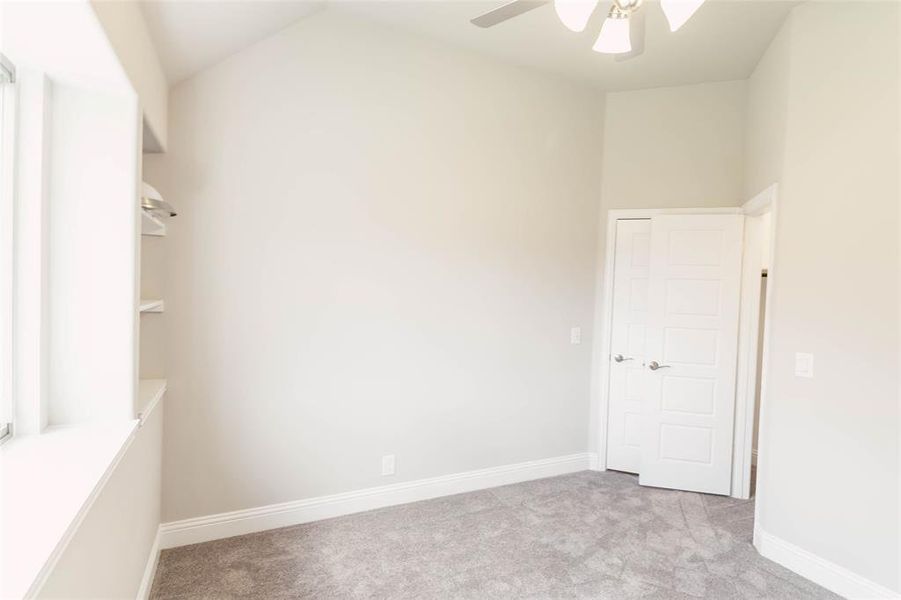 Unfurnished room with lofted ceiling, ceiling fan, and light carpet