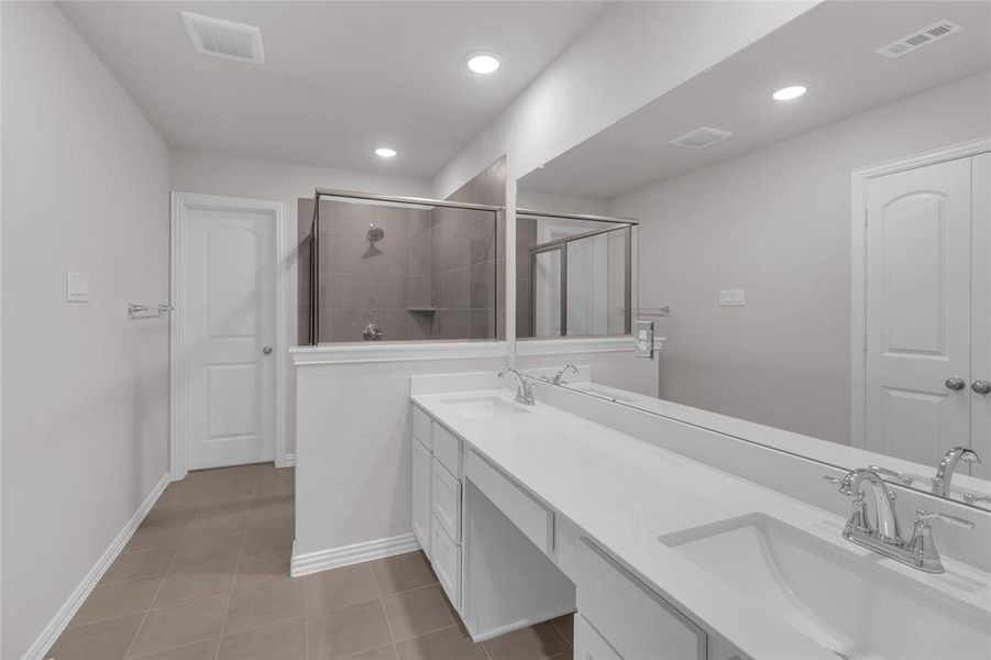 This photo shows a primary modern bathroom featuring a dual vanity with sleek fixtures, a large mirror, and a spacious shower area. The neutral color palette and recessed lighting create a clean, bright atmosphere.