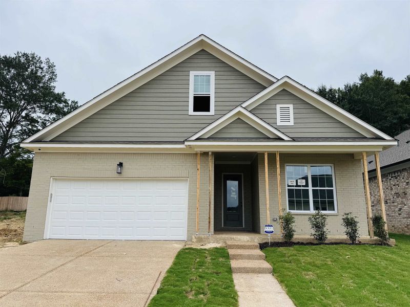 View of front of house featuring a garage, concrete driveway, brick siding, and a front yard