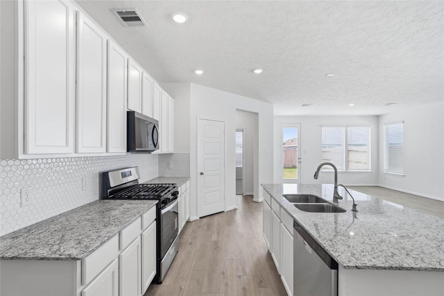 This bright, open kitchen is a chef's delight, complete with a large island, granite countertops, Woodmont Belmont cabinets in White, Whirlpool stainless steel appliances, and modern Daltile backsplash. This bright, open kitchen is a chef's delight, complete with a large island, granite countertops, Woodmont Belmont cabinets in White, Whirlpool stainless steel appliances, and modern Daltile backsplash.