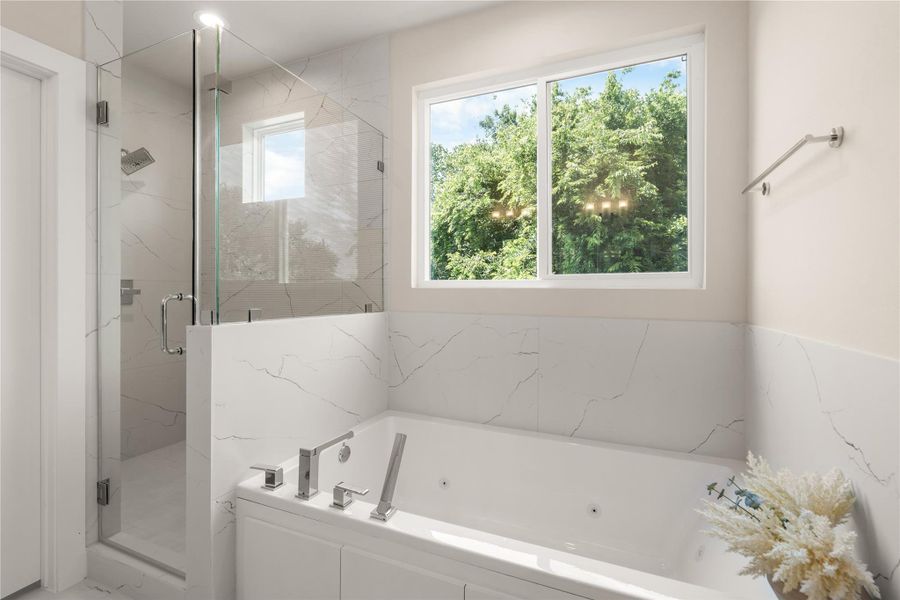 Spa-like primary bath featuring a floating double vanity, soaking tub & frameless glass shower all wrapped in elegant marble-inspired tile for a clean, modern finish.