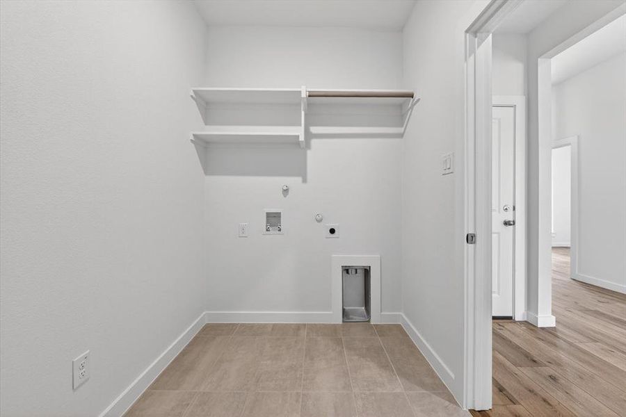 Dedicated laundry area featuring ceramic tile flooring and crisp white walls