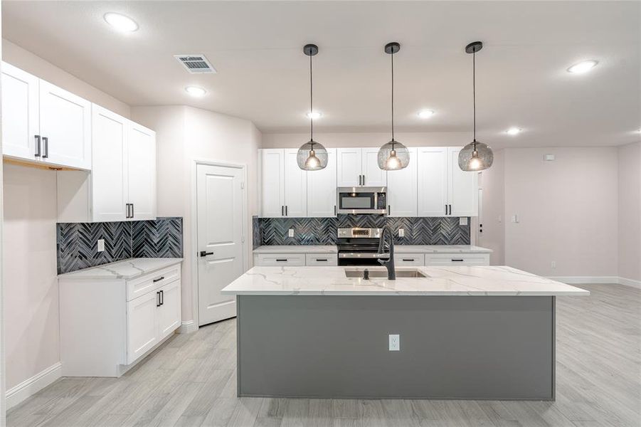 Kitchen with white cabinetry, pendant lighting, and appliances with stainless steel finishes