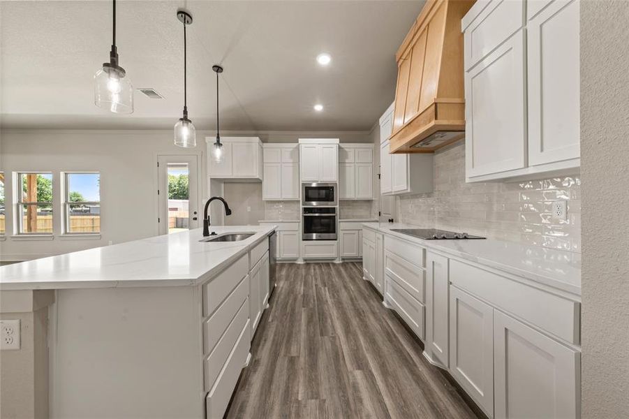 Modern kitchen featuring white shaker cabinetry, light-toned countertops, and wood-finish flooring Modern kitchen featuring white shaker cabinetry, light-toned countertops, and wood-finish flooring