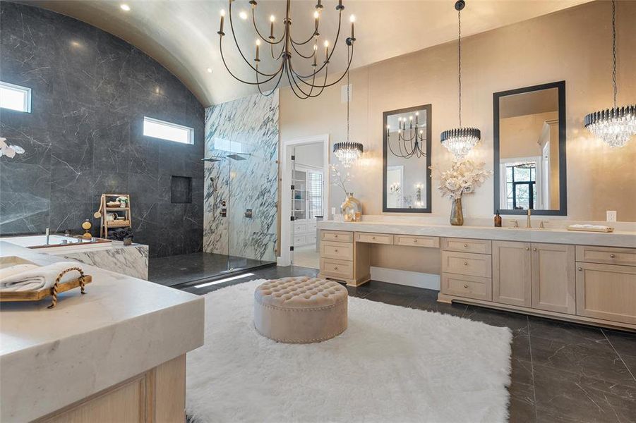 Bathroom with vanity, a marble finish shower, vaulted ceiling, and a chandelier