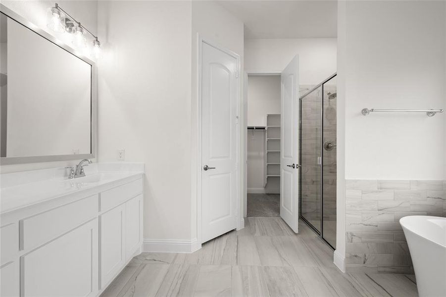 Bathroom featuring a stall shower, vanity, a freestanding tub, and a spacious closet Bathroom featuring a stall shower, vanity, a freestanding tub, and a spacious closet