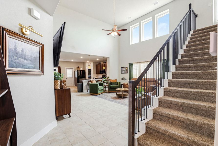 Carpeted staircase with black wrought custom iron balusters and wood-finish railing