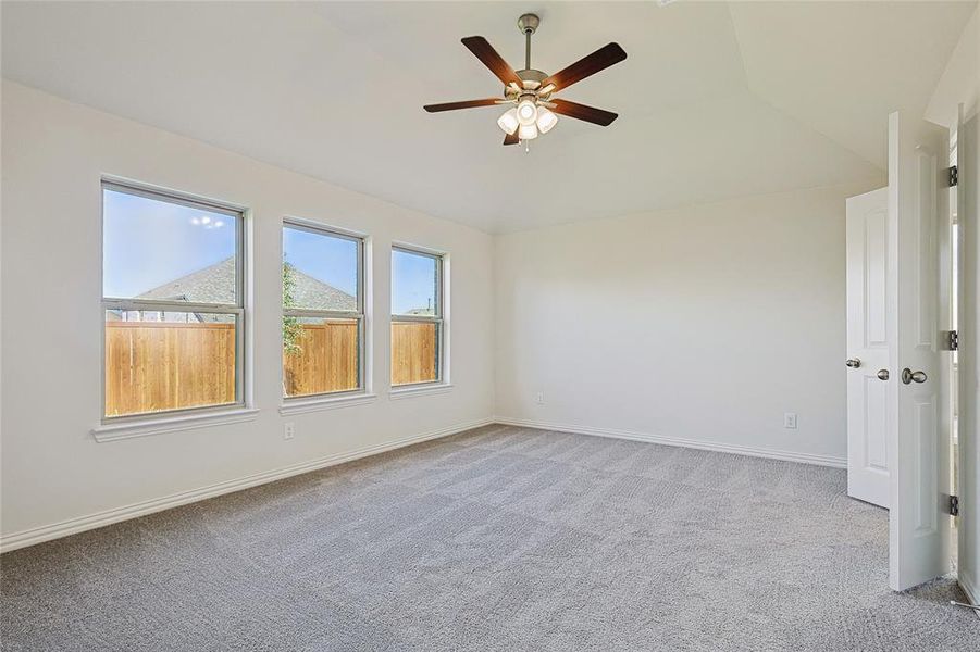 Spare room with ceiling fan, light colored carpet, and vaulted ceiling