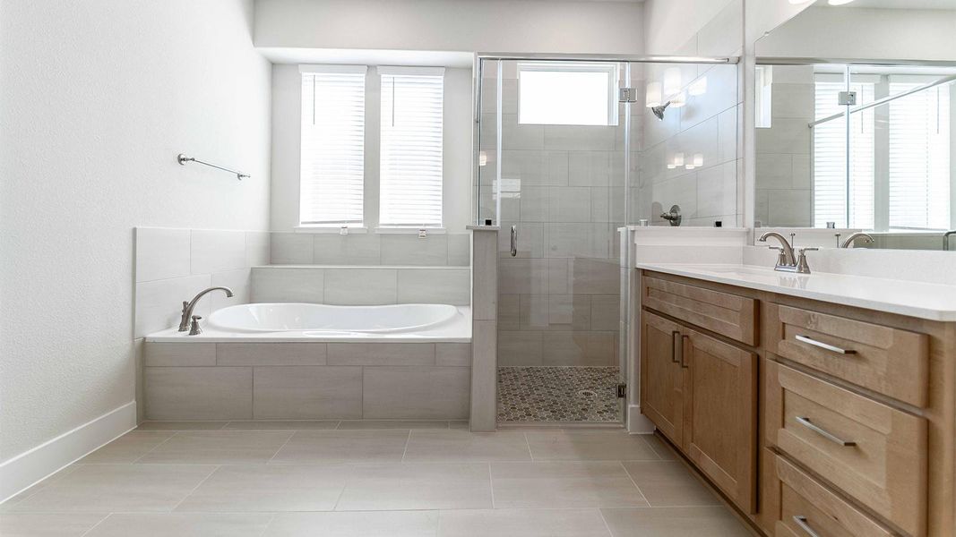Bathroom featuring vanity, a stall shower, light tile patterned floors, and a garden tub Bathroom featuring vanity, a stall shower, light tile patterned floors, and a garden tub