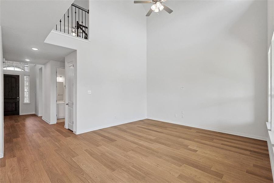 Empty room featuring light hardwood / wood-style flooring, ceiling fan, and a towering ceiling