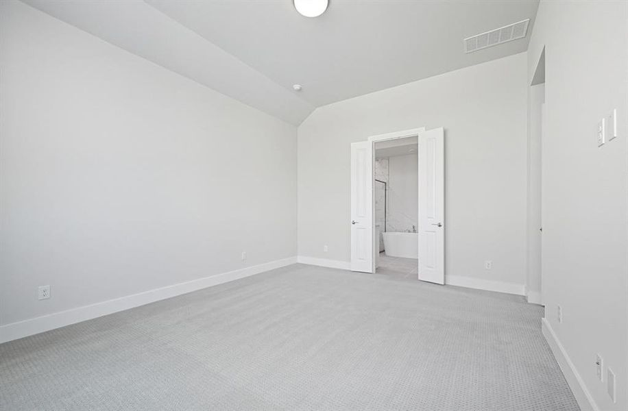 Unfurnished bedroom featuring light colored carpet, vaulted ceiling, and ensuite bath Unfurnished bedroom featuring light colored carpet, vaulted ceiling, and ensuite bath