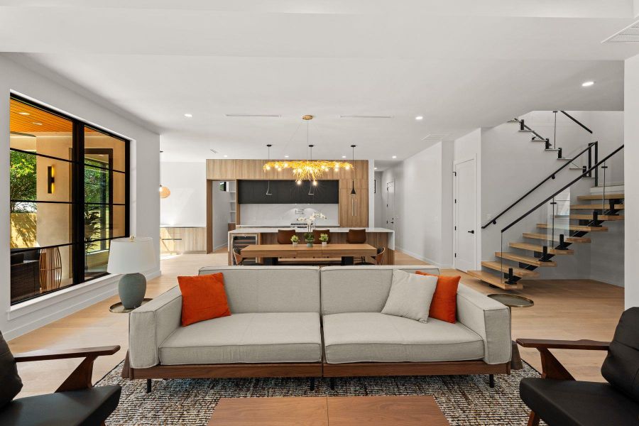 An open floor plan connects the living area with a modern kitchen and floating staircase.