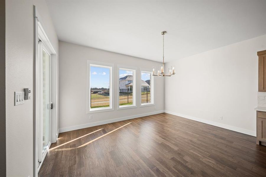 Unfurnished dining area featuring a chandelier and dark wood-style floors