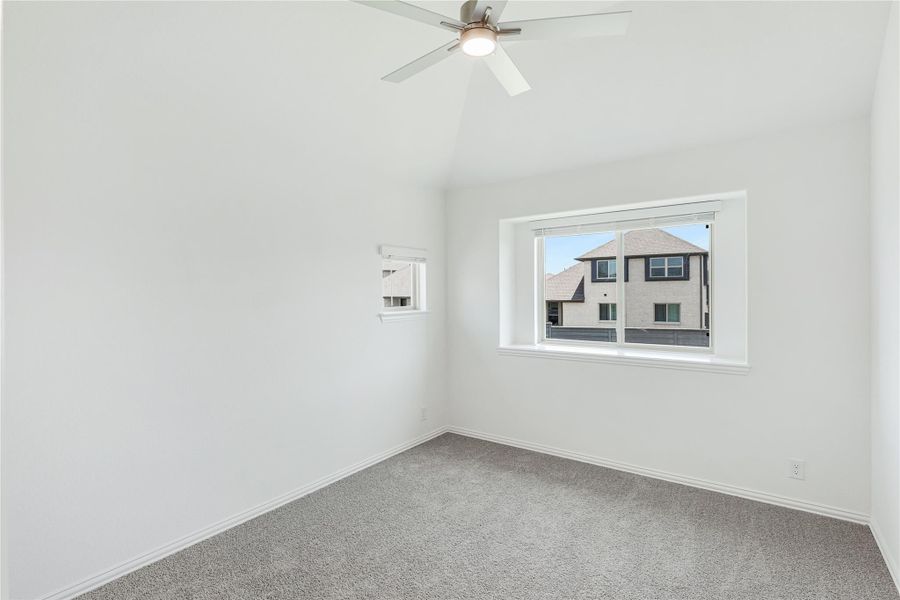 Empty bedroom with vaulted ceiling, ceiling fan, gray carpet, and two windows Empty bedroom with vaulted ceiling, ceiling fan, gray carpet, and two windows