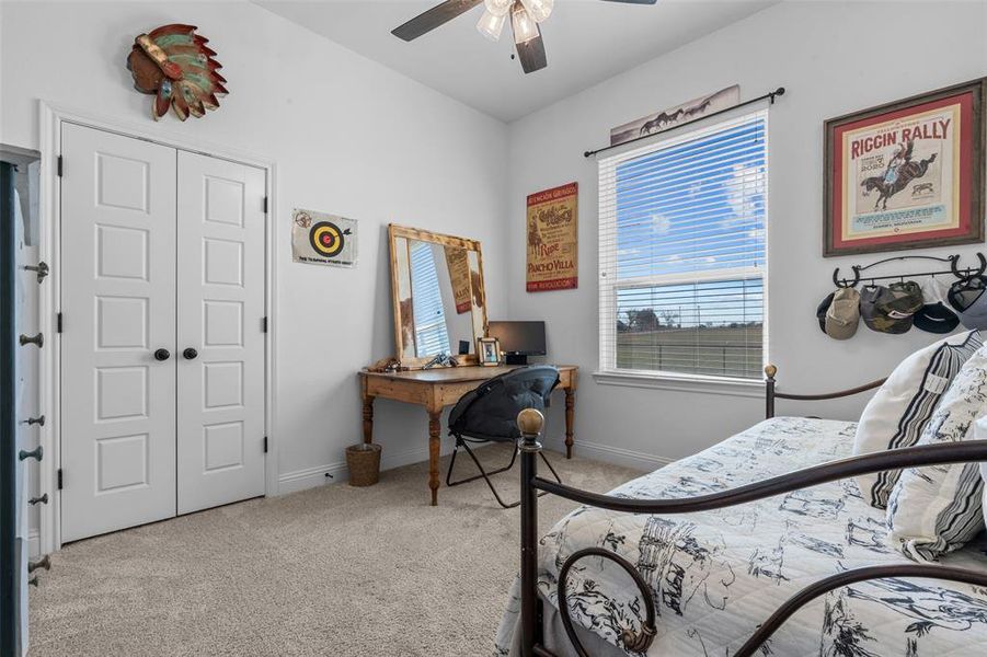 Carpeted bedroom with ceiling fan and a closet