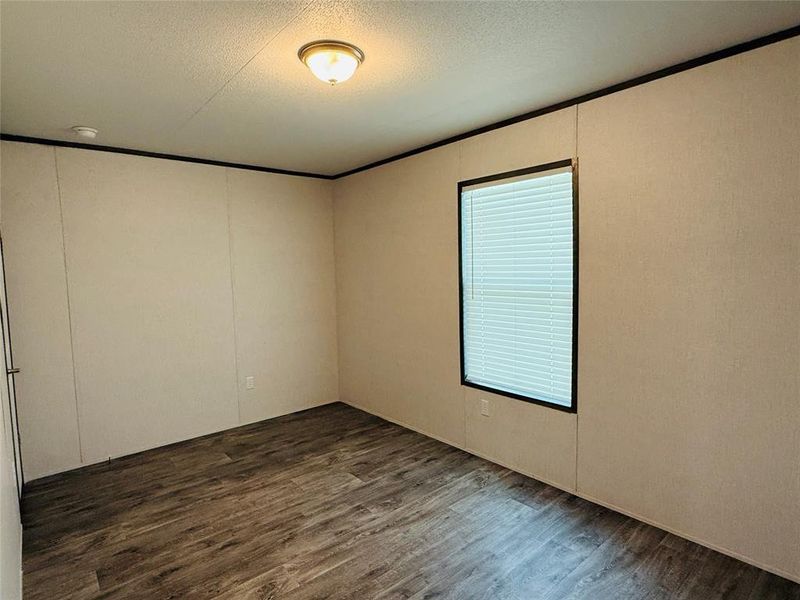 Unfurnished room featuring ornamental molding, a textured ceiling, and wood finished floors
