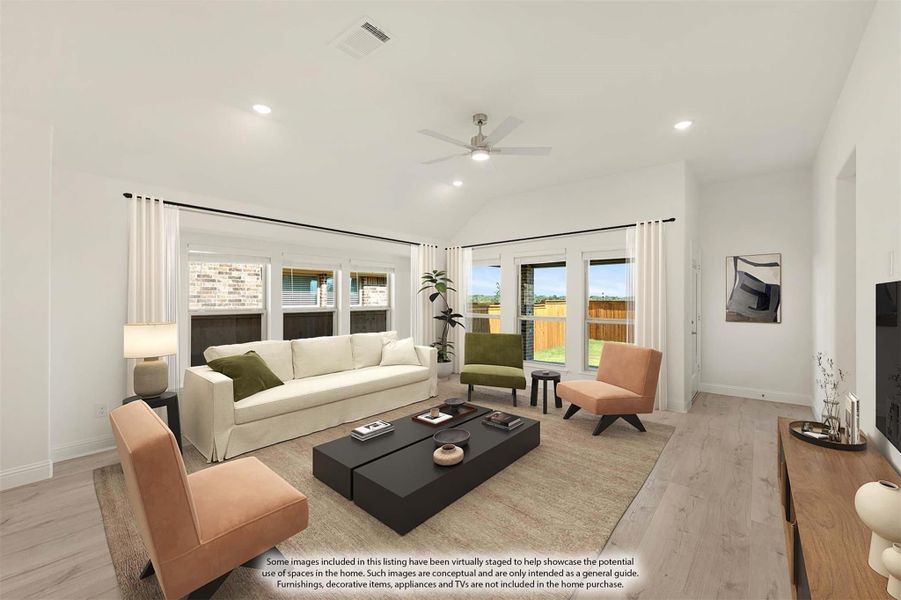 Living room with vaulted ceiling, ceiling fan, light wood floors, and large windows with backyard views