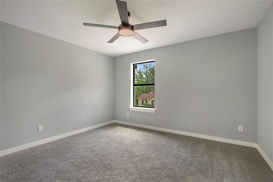 Carpeted empty room featuring ceiling fan