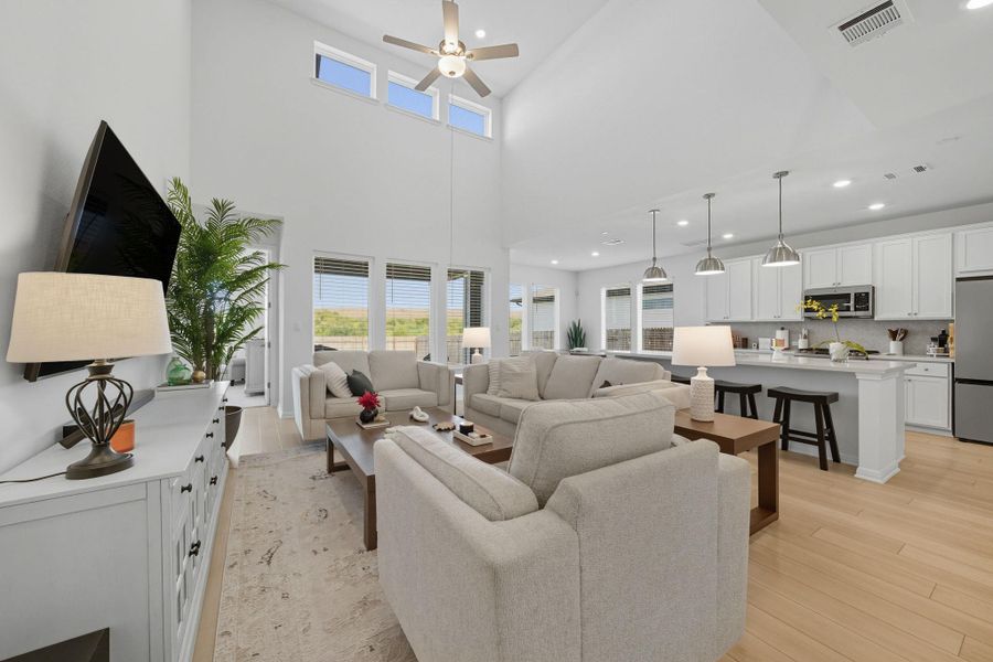 Living room featuring light wood-style flooring, recessed lighting, a high ceiling, and a ceiling fan Living room featuring light wood-style flooring, recessed lighting, a high ceiling, and a ceiling fan