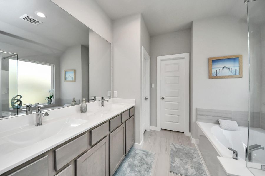 The primary bath offers a dual-sink vanity, a deep soaking tub and a separate glass-enclosed shower.