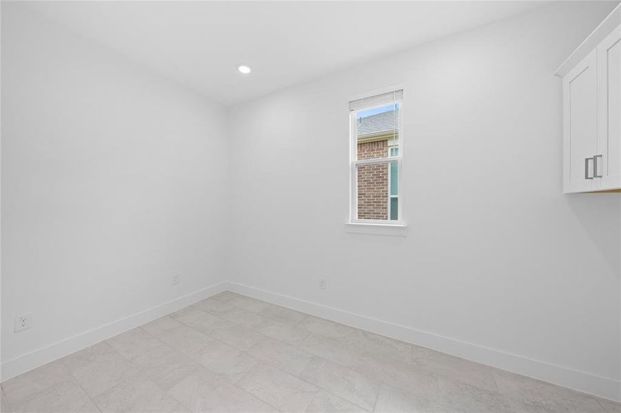 Room featuring light-toned tile flooring, clean white walls, and a single recessed ceiling light