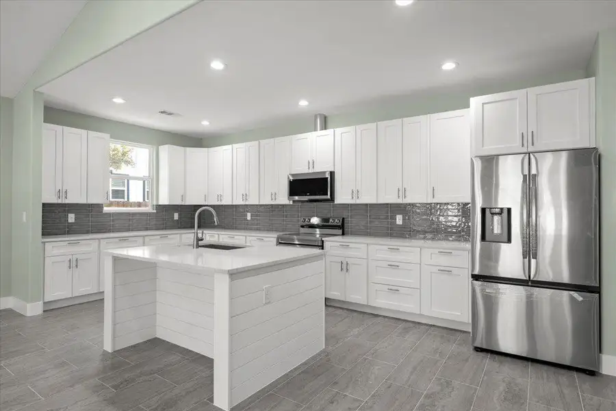 Kitchen featuring appliances with stainless steel finishes, white cabinets, decorative backsplash, and recessed lighting