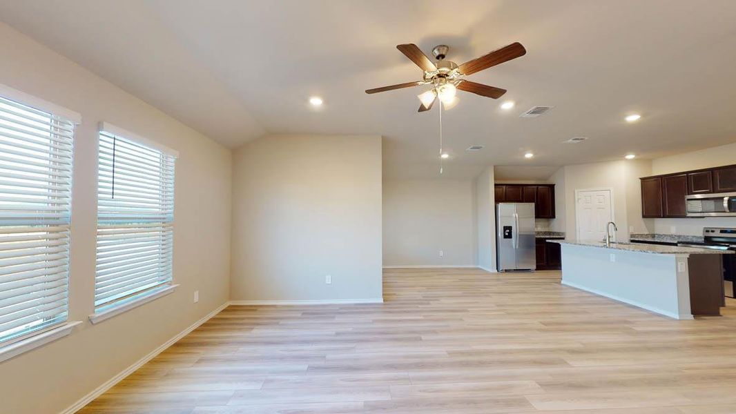 Kitchen featuring dark brown cabinets, a kitchen island with sink, open floor plan, light wood-type flooring, and recessed lighting