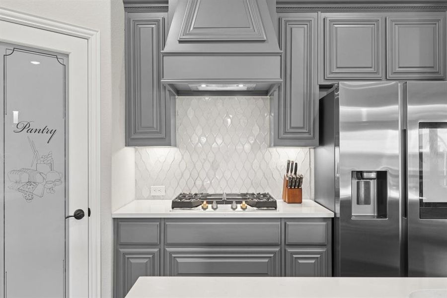 Kitchen featuring appliances with stainless steel finishes, gray cabinetry, custom range hood, and tasteful backsplash Kitchen featuring appliances with stainless steel finishes, gray cabinetry, custom range hood, and tasteful backsplash